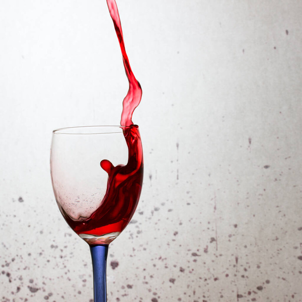vierte bellamente un vino tinto en el borde de una espectacular salpicadura de vidrio y un largo flujo de concepto de alcohol - Foto, Imagen