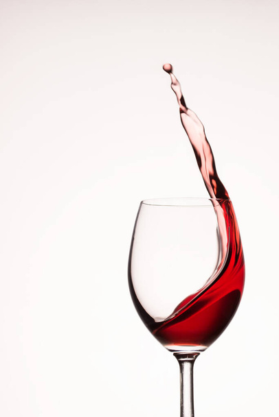 jasné cákání červeného vína v průhledném skle na šedém pozadí - Fotografie, Obrázek