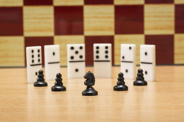 schaken paard en pionnen op een achtergrond van dominostenen en gaming boards concept van populaire bordspellen spannend en logisch - Foto, afbeelding