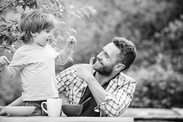 family dinner time. father and son eating outdoor. happy fathers day. Little boy with dad eat cereal. summer picnic. Morning breakfast. healthy food and dieting. Childrens day. Happy family together - Foto, immagini