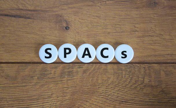 SPACs symbol. White circles with words 'SPACs, special purpose acquisition companies' on beautiful wooden background, copy space. Business and SPACs, special purpose acquisition companies concept. - Photo, image