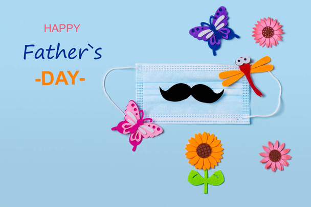 Protective face mask with mens mustache and summer elements on a blue background. The concept of celebrating a birthday or father's day during the coronavirus pandemic. Flat lay. - Photo, Image