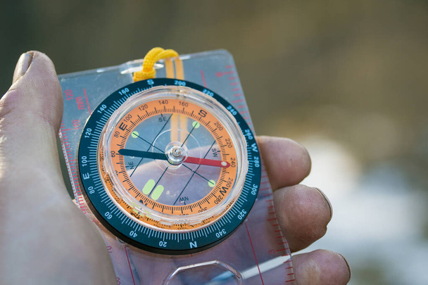 Kompass in der Hand auf verschwommenem Hintergrund des Naturkonzepts von Wanderungen und Ausflügen - Foto, Bild