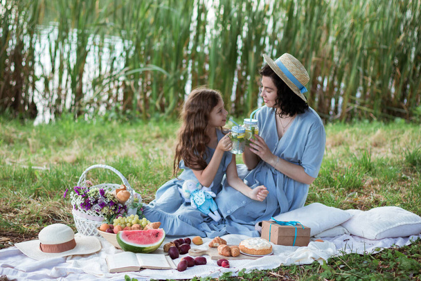 Nehrin kıyısındaki parkta piknik yapan bir anne ve kız. - Fotoğraf, Görsel