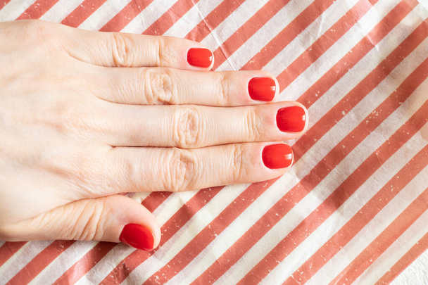 female hands with red manicure close up on isolated colored background - Photo, Image