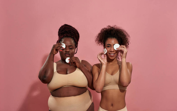 Couple of female afro friends hiding their faces under cotton sponges - Foto, immagini