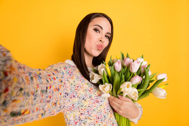 Photo portrait of woman with pouted lips taking selfie with tulips bouquet isolated on bright yellow color background - Foto, Imagen