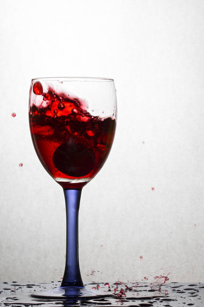 Fallen grapes in a glass of red wine formed a beautiful splash of bright alcoholic beverage - Foto, afbeelding