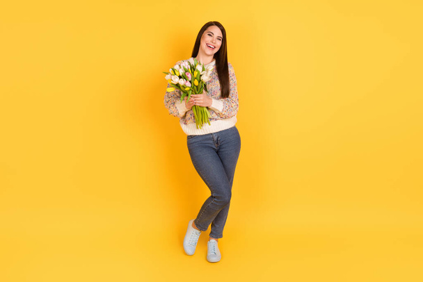 Full length photo of charming happy lady hold hands bouquet tulips holiday spring isolated on yellow color background - Foto, imagen