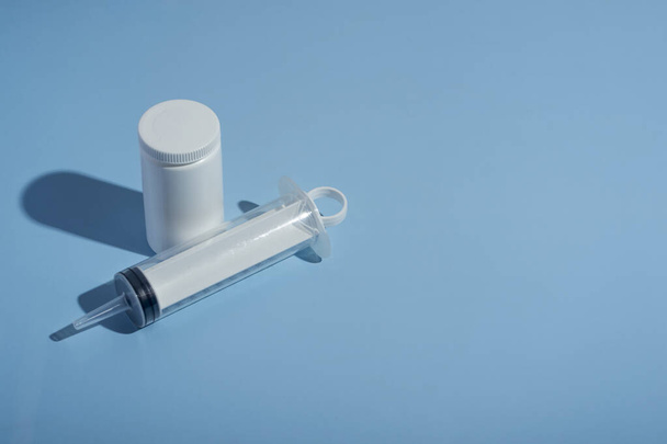 Pills, syringe for a catheter on a blue medical background. close-up, top view. Medical syringe, tube with vitamins - Photo, Image