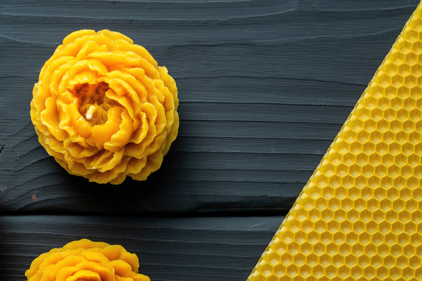 Velas de flores decorativas feitas de cera de abelha com um aroma de mel para interior e tradição no fundo de madeira escura. - Foto, Imagem
