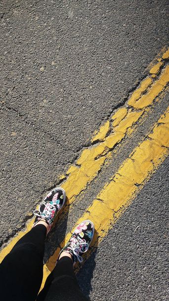 pieds restant sur des lignes doubles jaunes. La personne reste au milieu de la route.  - Photo, image