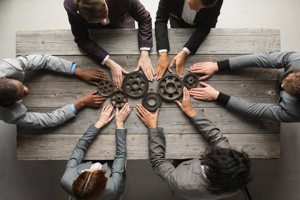 Business people connect gear together at meeting table, success cooperation teamwork concept - Фото, зображення