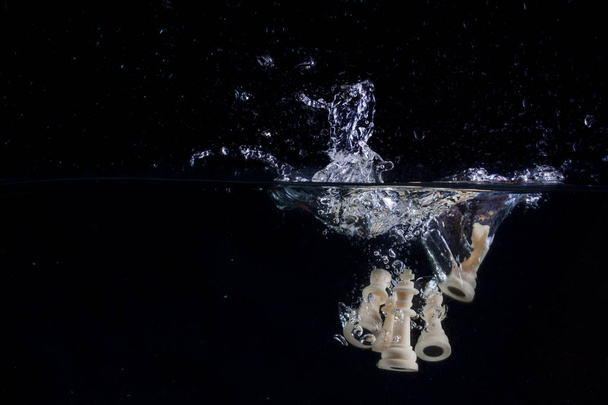 pièces d'échecs sous une belle éclaboussure d'eau sur un fond sombre passe-temps et concept de sport - Photo, image