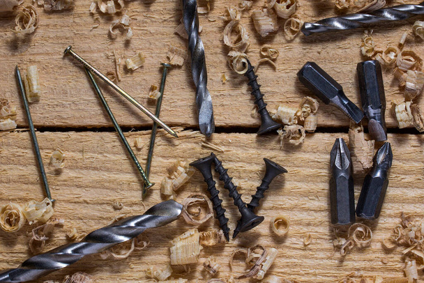 metalen gereedschappen boren bit zelftappende schroef en spijker close-up op houten werkplek concept van de industrie en houtbewerking - Foto, afbeelding