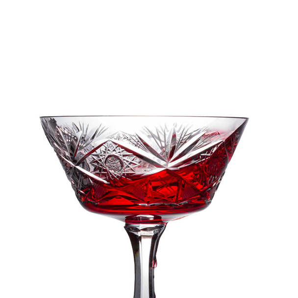 spruzzata di vino rosso in un bicchiere d'annata sul cui piede scorre una goccia d'acqua su fondo bianco - Foto, immagini