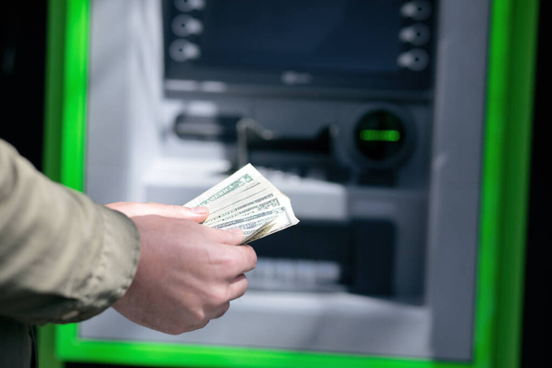 człowiek stoi przy bankomacie z pieniędzmi w rękach - Zdjęcie, obraz