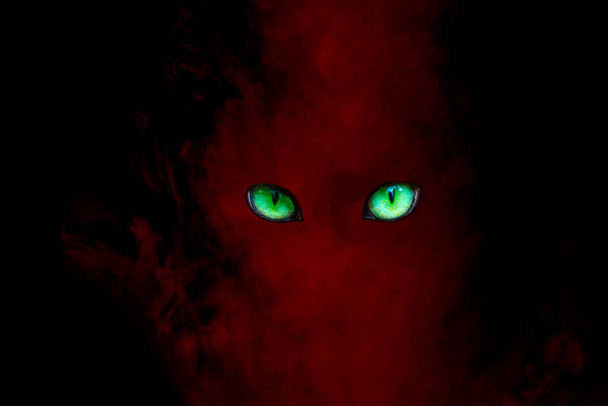 зеленые сверкающие глаза в красном призраке от абстракции паров сигарет для дизайнерской концепции таинственного - Фото, изображение