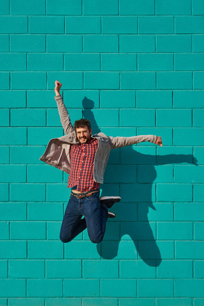 Portrait d'un homme caucasien joyeux sautant isolé sur un fond turquoise. Photo de haute qualité - Photo, image