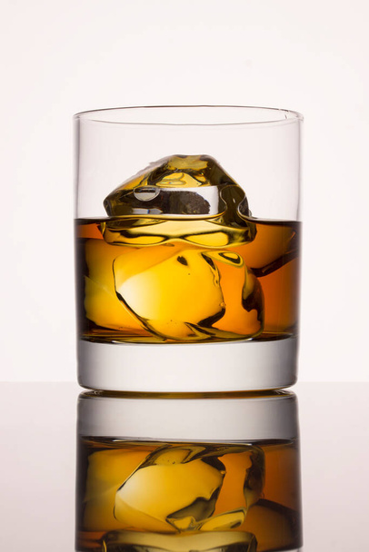 glass of whiskey with ice on a gray background a delicious alcoholic drink - Zdjęcie, obraz