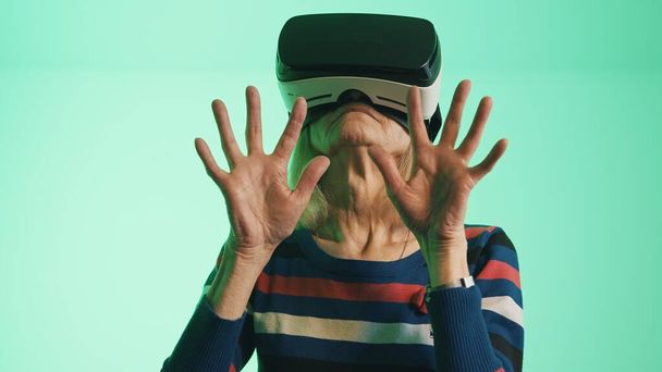 Stara kaukaska kobieta z zestawem VR dotykającym powietrza - Zdjęcie, obraz