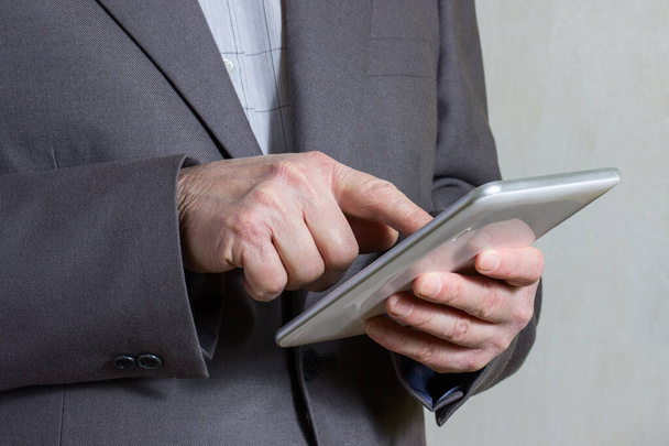 hombre de negocios en una chaqueta gris presiona en la pantalla de la tableta con su dedo índice el concepto de industria y tecnología - Foto, imagen