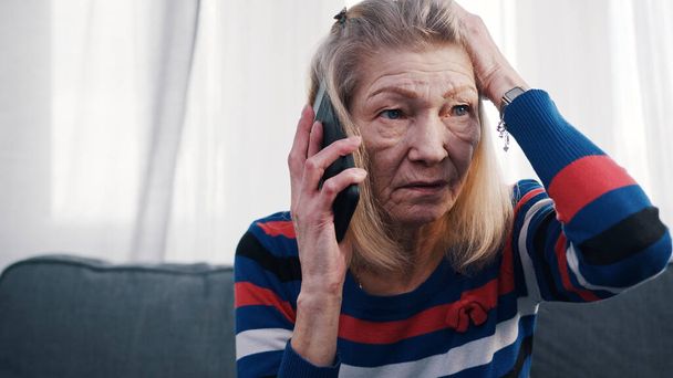 Telefon etmek için akıllı telefon kullanan yaşlı bir kadın. Kötü haberler alıyorum. - Fotoğraf, Görsel