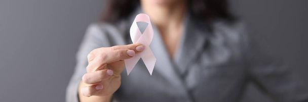 Woman in gray business suit holding pink ribbon in her hands closeup - Photo, Image