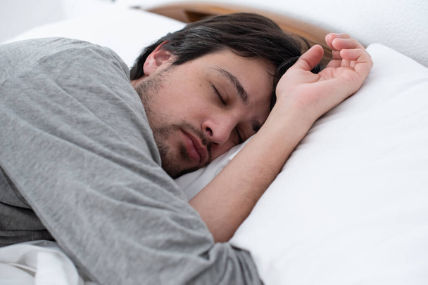 Молодой человек мирно спит в постели - Фото, изображение