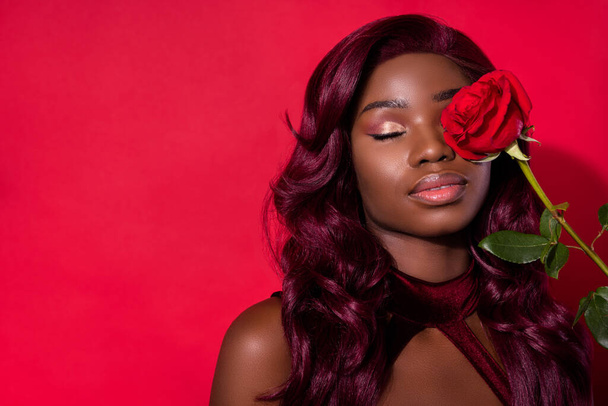Photo of afro american charming pretty luxury young woman cover eye rose copyspace isolated on red color background - Valokuva, kuva