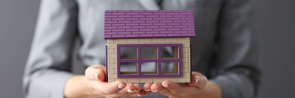 Жінка тримає дерев'яний іграшковий будинок в її руках крупним планом
 - Фото, зображення