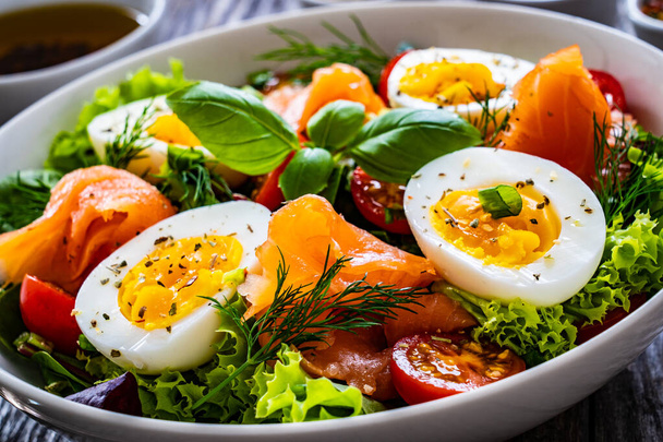 Salmon salad - smoked salmon hard boiled eggs and green vegetables on wooden table  - Foto, immagini