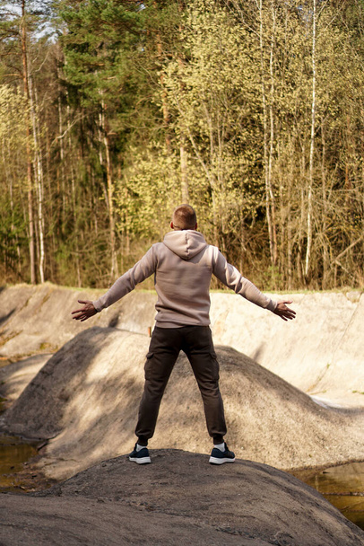 Młody człowiek stoi na małej górze w rejonie górskiej rzeki - Zdjęcie, obraz