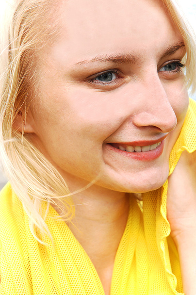 A close-up heath shot of an young blond pretty woman in an bright yellow blouse, happy smiling. - Fotoğraf, Görsel