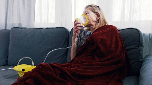 Oudere vrouw met zuurstofmasker bij haar thuis - Foto, afbeelding