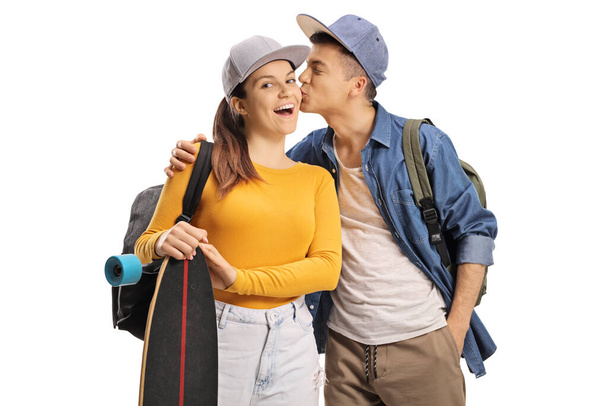 Male student kissing a female skater with a longboard isolated on white background - Photo, image