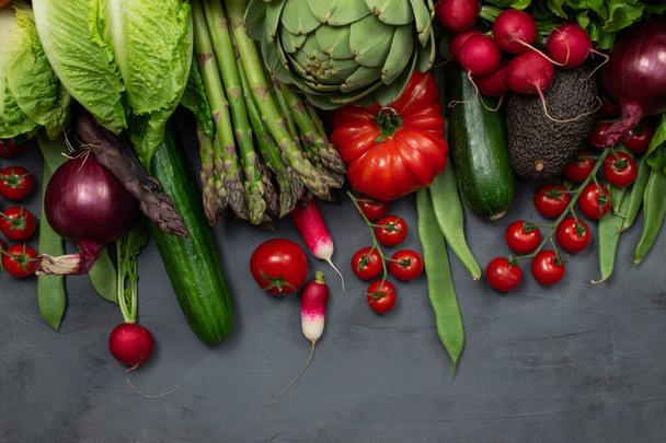 Erilaiset luomuvihannekset - parsa, tomaatit kirsikka, avokado, artisokka, pippuri, lime, sitruuna, suola harmaalla pohjalla. Ruoka maine kopioi tilaa, ylhäältä näkymä. Raaka vegaani kasvissyöjä käsite - Valokuva, kuva