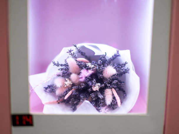 Close-up of a bouquet of flowers in a box in a self-service vending machine. - Fotó, kép