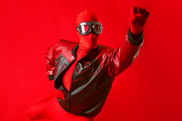 Un súper héroe divertido en un maillot rojo y gafas protectoras volando hacia adelante. - Foto, imagen