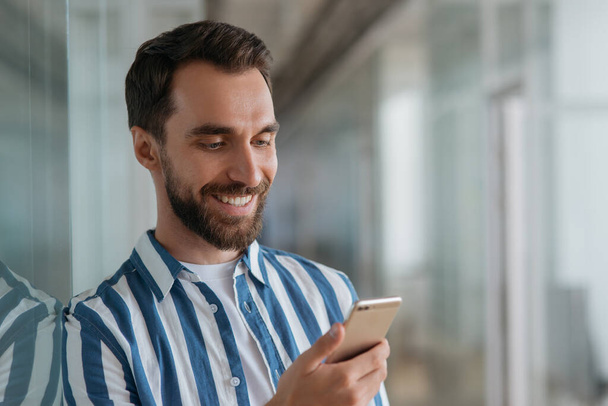 Handsome smiling business man using mobile phone, communication online. Happy bearded guy making reservation - Φωτογραφία, εικόνα