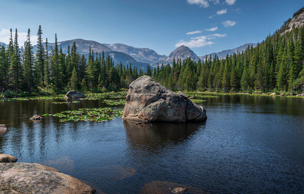 Lower twin lake and boulder, surrounded by a dense forest, views of Eagles Beak peak in the background - Photo, Image