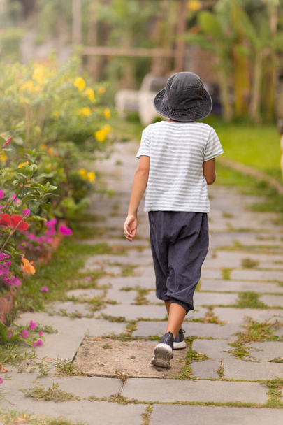 Rear view of a boy walking in a tropical garden - Foto, Imagen