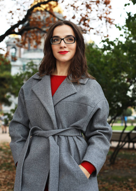 Close-up portrait of young woman in elegant gray coat standing on the street in autumn day. - Foto, Imagen