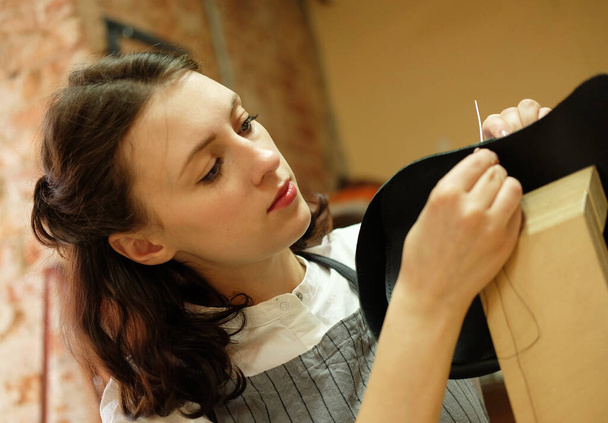 young woman works in a bag making studio, cuts out details - Zdjęcie, obraz