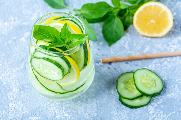 Fresh cool detox water drink with cucumber and lemon. glass of Lemonade with basil and mint leaves. Concept of proper nutrition and healthy eating. Fitness diet. - Foto, Bild