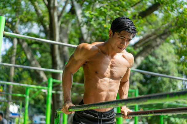 A muscular man who does pull ups to work his biceps and triceps muscles - Photo, Image