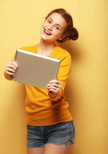 Young woman taking selfie with digital tablet over yellow background - Фото, изображение