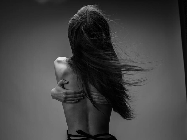 naakte vrouw knuffelen zichzelf met armen in zwart-wit foto - Foto, afbeelding