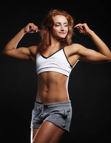 Photo of cheerful young red haired woman dressed sportwear over black background. - Fotó, kép
