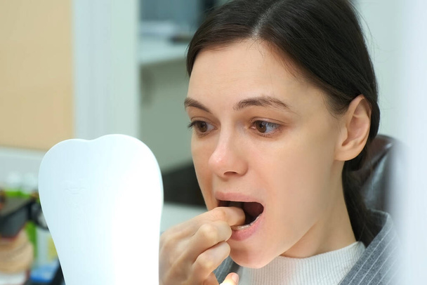 Mulher na odontologia remove treinador dentes de silicone de sua boca por si só. - Foto, Imagem